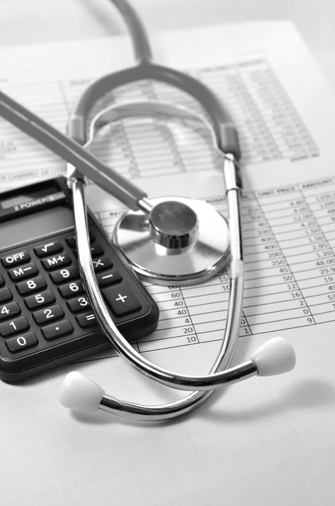 calculator, stethoscope and healthcare bill