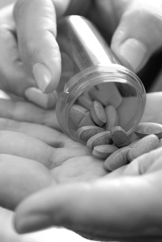 hands holding a prescription bottle and pills